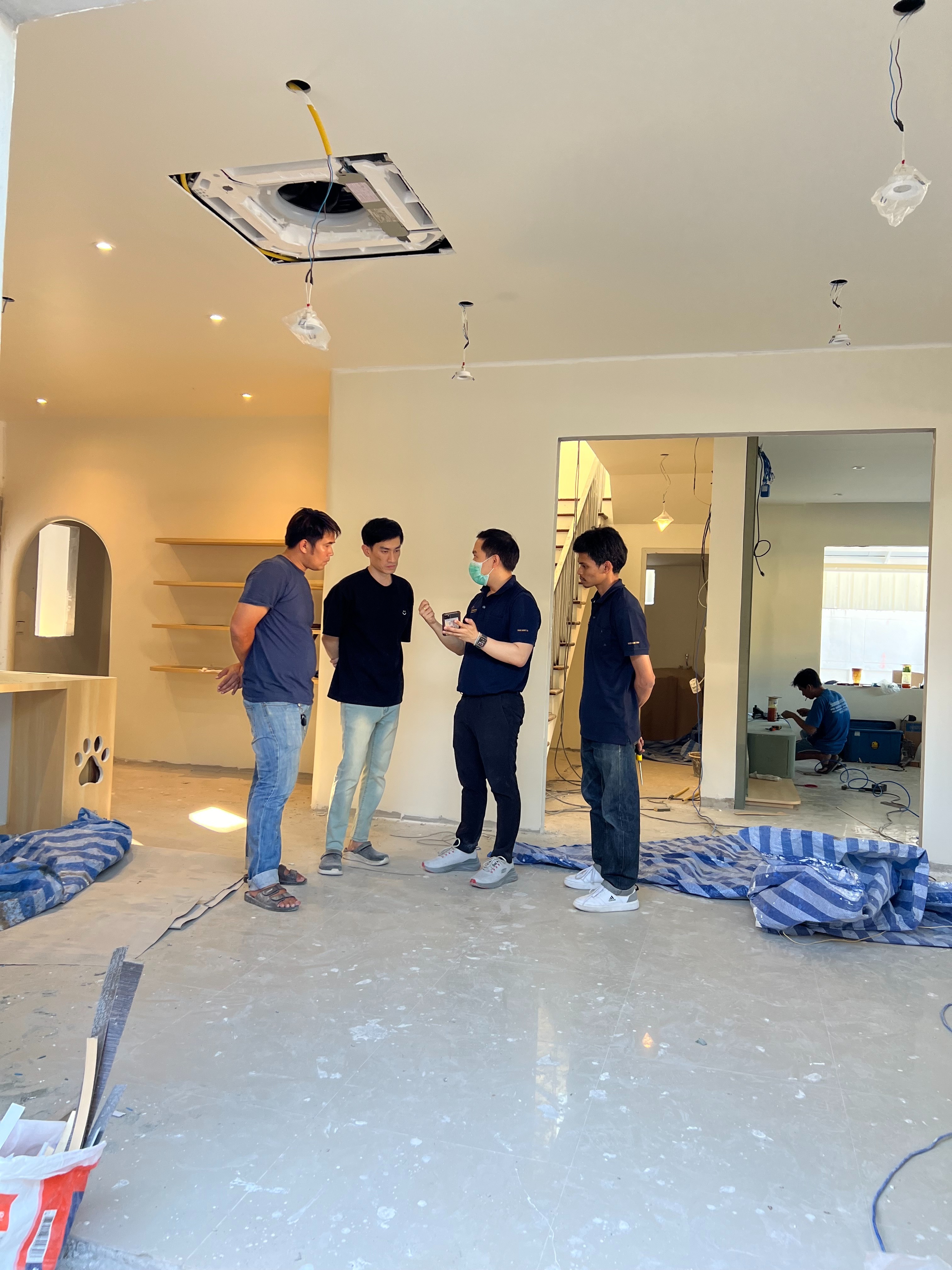 ทีม PST กำลังยืนคุยกับลูกค้าภายในบ้าน ด้านหลังเป็นฝ้าที่เปิดไว้รอใส่แอร์ Cassette